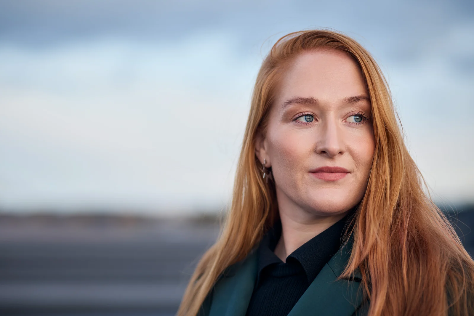 Porträtt av en rödhårig medarbetare på Armatec utomhus mot en blå himmel