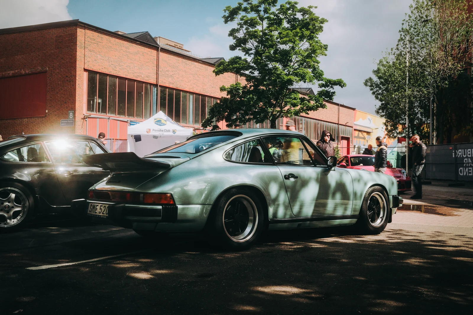 Ljusgrön klassisk sportbil parkerad i solen utanför en tegelbyggnad på Gothenburg Classic Car Weekend
