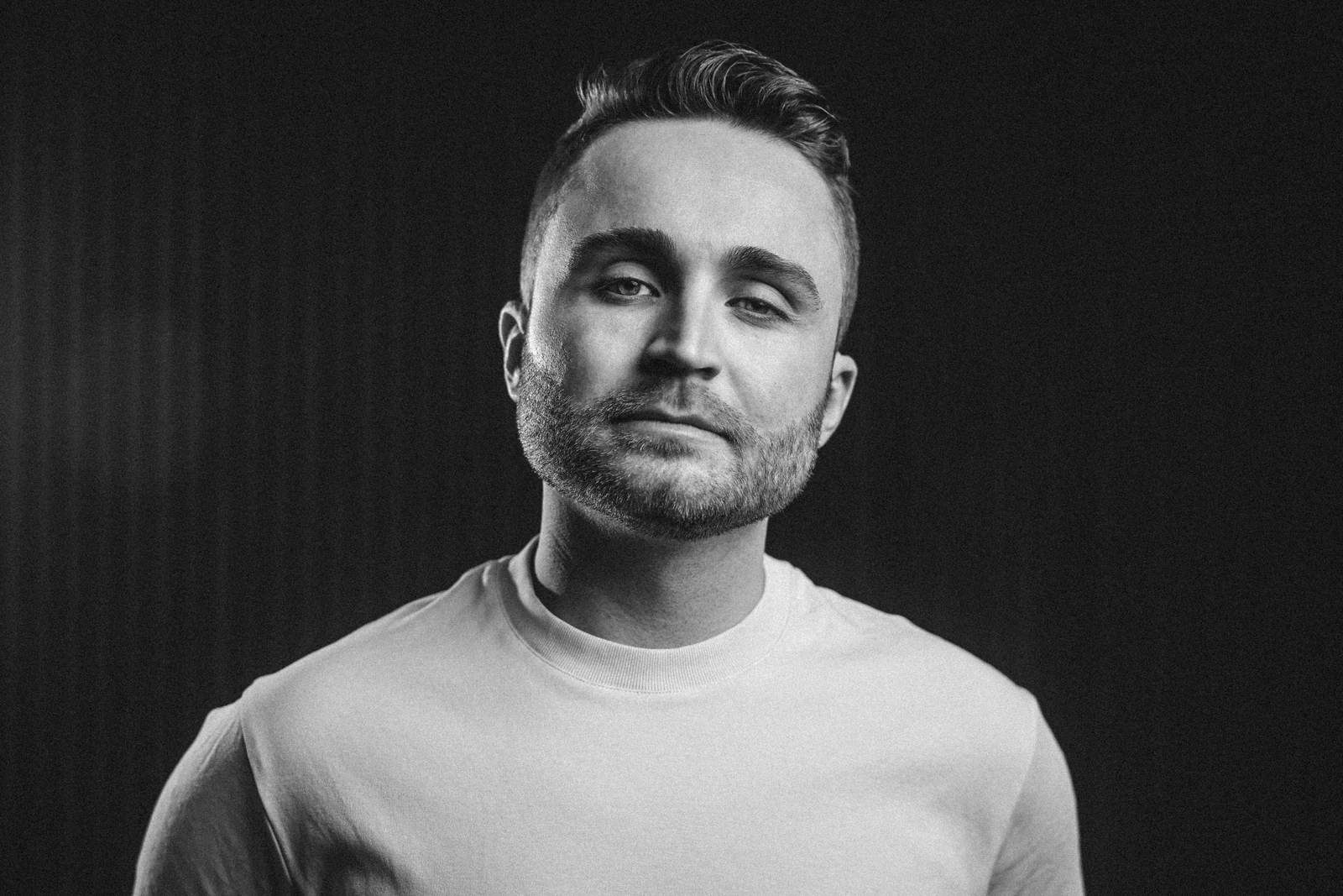 Porträtt av Nicklas Dahlgren i vit t-shirt mot mörk bakgrund