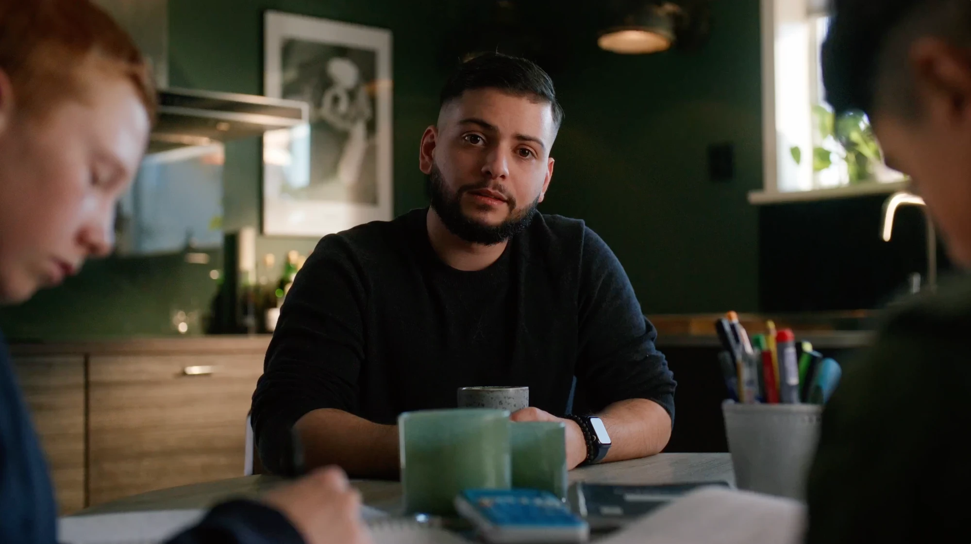 Ung man vid ett köksbord med matteböcker